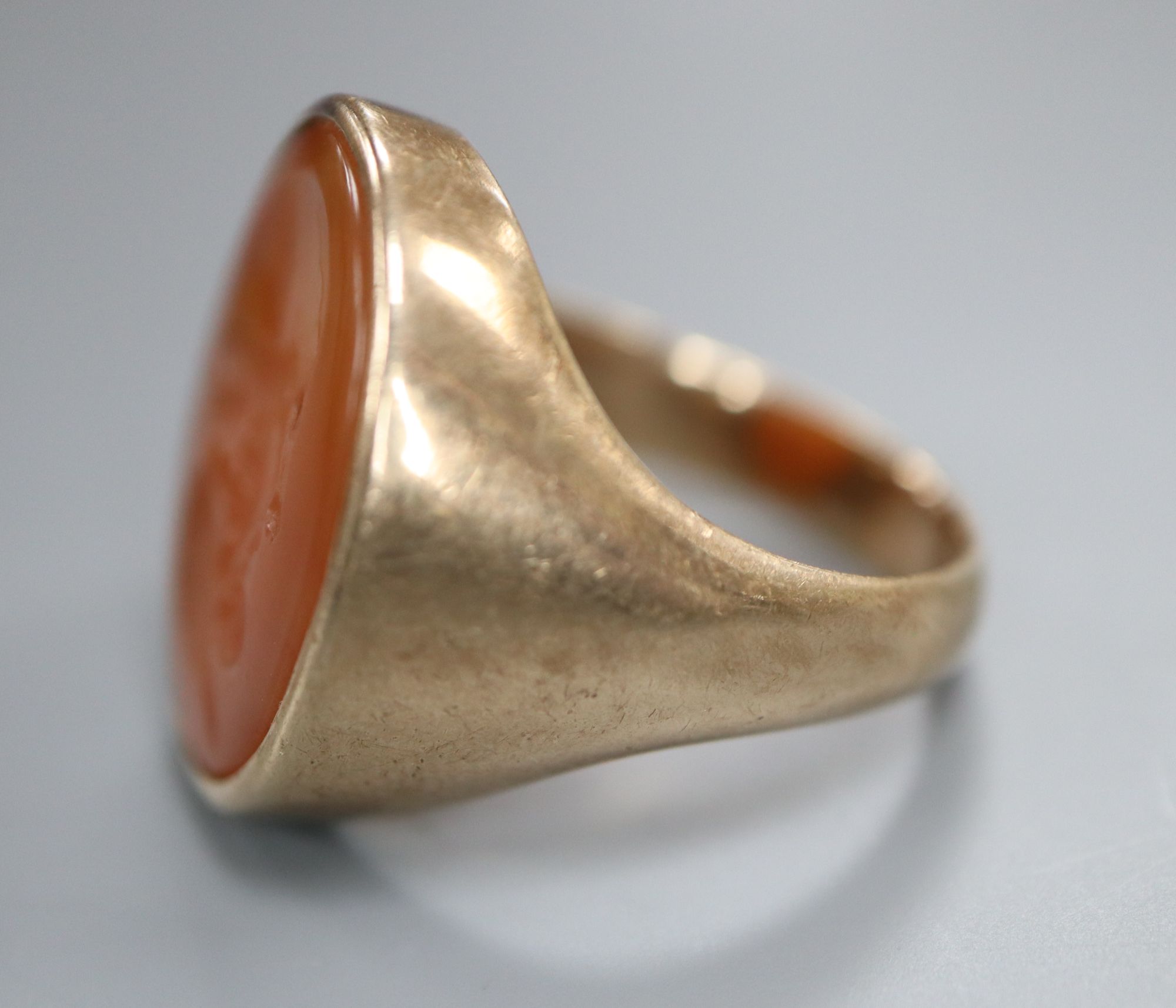 A late 19th century yellow metal and oval carnelian intaglio ring, carved with the head of a gentleman to sinister, size R,
